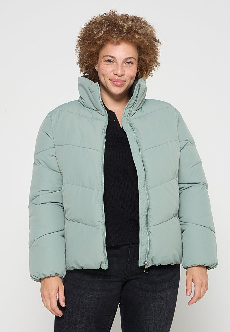 Hellgrüne Steppjacke mit hohem Kragen, vertikalen abgesteppten Abschnitten und einem Reißverschluss auf der Vorderseite, gefertigt aus einem glatten, isolierten Material.