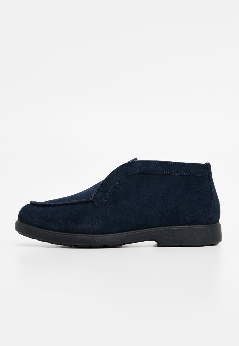 Navyblaue Wildleder-Ankle Boots mit glatter Oberfläche, in einem Slip-On-Design und mit runder Zehenform. Schwarze Gummisohle mit minimalem Profil.