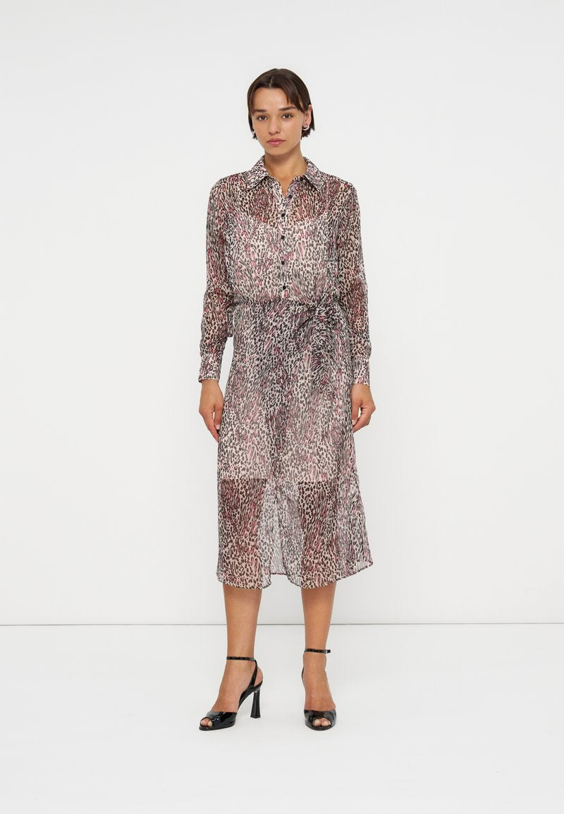 Frau steht, trägt ein langärmliges, geknöpftes Midi-Kleid mit Animal-Print und Taillenschleife sowie schwarze offene Sandalen mit Absatz.