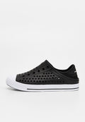 Schwarzer Slip-On-Sneaker mit mehreren runden Perforationen, weißer Gummisohle und weißer Zehenkappe, von der linken Seite betrachtet.