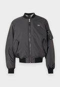 Schwarze Bomberjacke mit Frontreißverschluss, gerippten Bündchen und Saum, Pattentaschen und einer Reißverschlusstasche mit Schlüsselring am linken Ärmel.