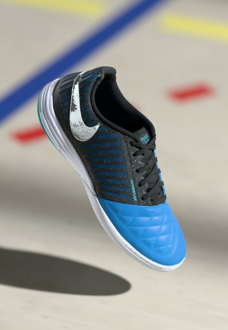 Blau und schwarze Sportschuhe mit gestepptem Muster, silbernem Nike-Swoosh und gestreiftem Muster an der Oberseite. Verfügt über schwarze Schnürsenkel und eine weiße Sohle.