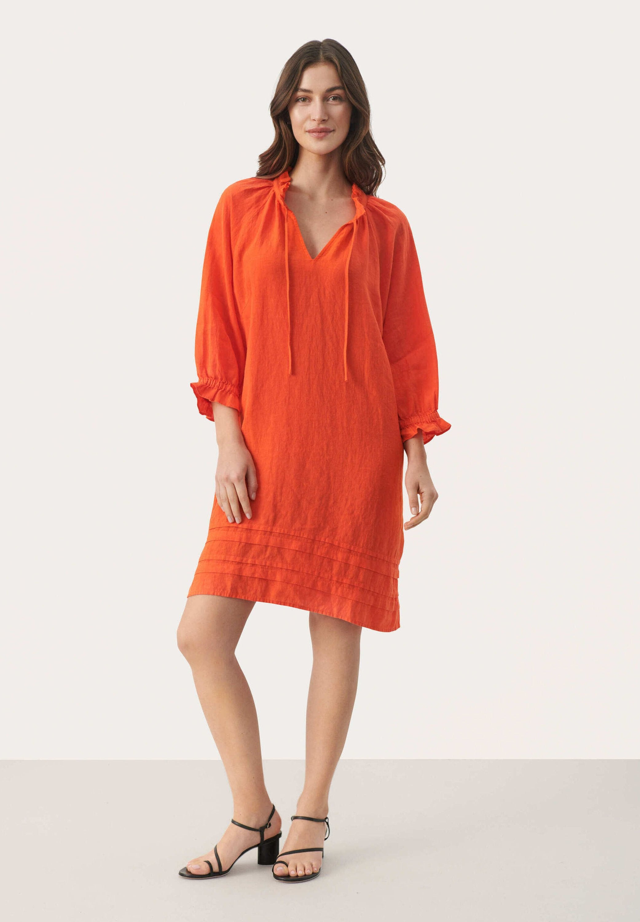 Helles orange Leinenkleid mit V-Ausschnitt, Kordelzug am Hals und Dreiviertelärmel. Verfügt über gestreifte Details am Saum.