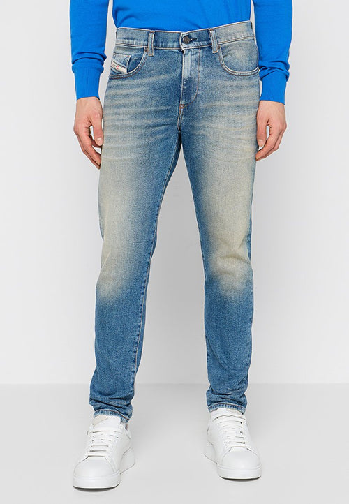 Hellblaue Jeans aus Denim mit einem ausgewaschenen Finish, ausgestattet mit fünf Taschen, einem Knopfverschluss und geradem Bein, getragen mit weißen Sneakers.