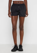 Schwarze Sportshorts mit glatter Textur, elastischem Bund und Kordelzug. Logobezug an der unteren linken Ecke. Getragen mit schwarzen Sneakers.