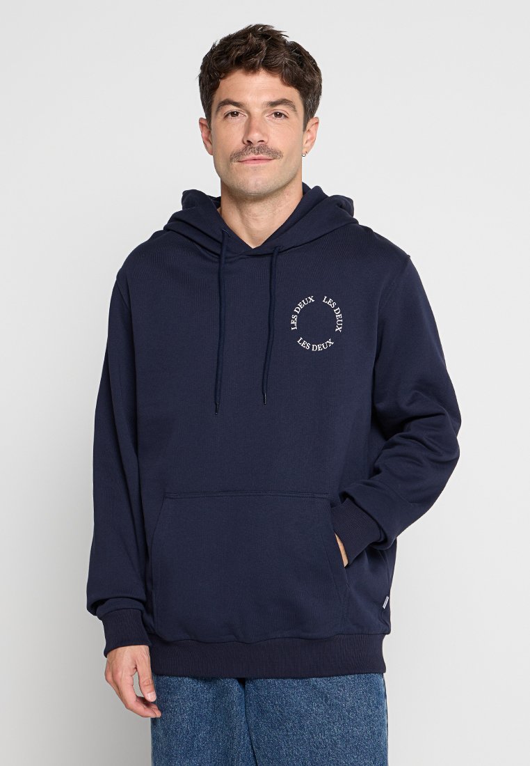 Marineblauer Kapuzenpullover mit Kängurutasche, Kordelzügen, gerippten Bündchen und rundem weißen Logo auf der Brust. Weicher Stoff mit einem lässigen Schnitt.