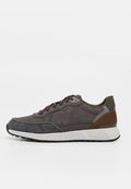 Brauner und grauer Freizeitsneaker mit weißer Sohle, Schnürdesign und braunem Fersenakzent, von der Seite auf einfarbigem Hintergrund gezeigt.