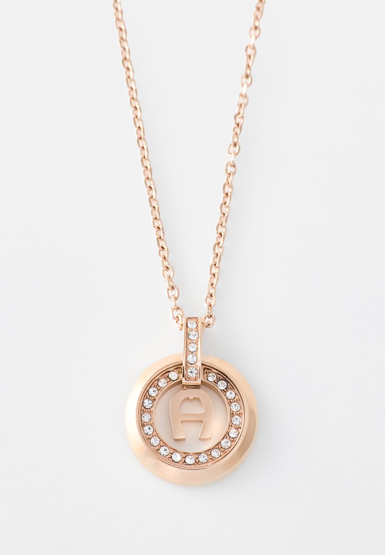 Halskette mit Anhänger aus Roségold, der ein kreisförmiges Design aufweist, akzentuiert mit klaren Strasssteinen und einem eingravierten Logo in der Mitte.