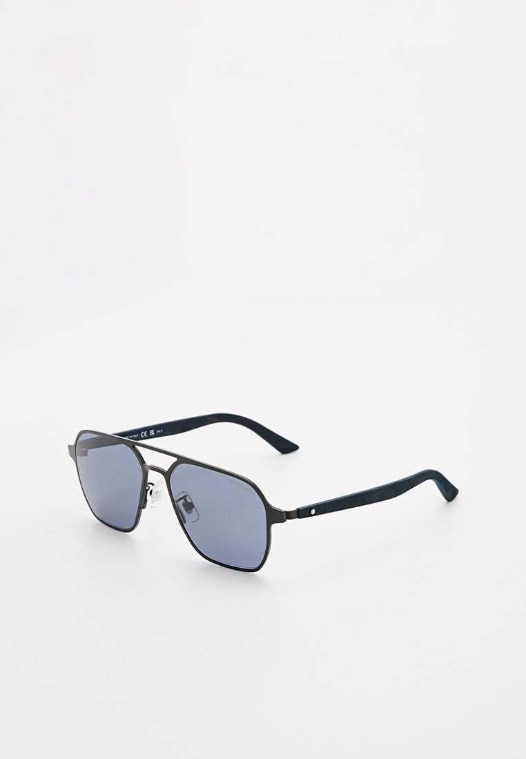 Schwarze Sonnenbrille mit Metallrahmen, dunklen rechteckigen Gläsern und strukturierten schwarzen Bügeln, die auf einer weißen Fläche nach rechts geneigt ruhen.