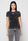 Schwarzes T-Shirt mit kurzen Ärmeln und strukturiertem Finish; verfügt über ein kleines, ovales Logo in Weiß und Rot auf der Brust. Getragen mit ausgefransten grauen Jeans.