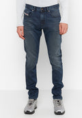 Dunkelblaue Jeans aus Denim mit Slim Fit, fünf Taschen und dezenten Used-Effekten. Kombiniert mit grauen Turnschuhen.