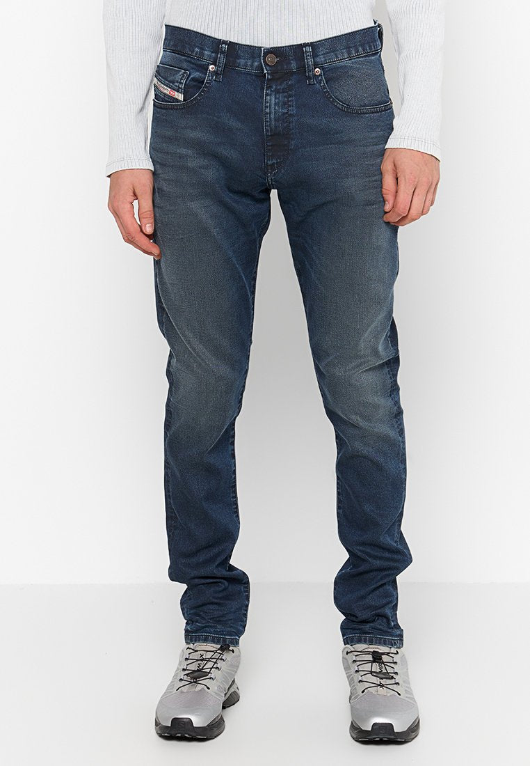 Dunkelblaue Jeans aus Denim mit Slim Fit, fünf Taschen und dezenten Used-Effekten. Kombiniert mit grauen Turnschuhen.