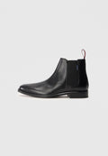 Schwarze Leder-Chelsea-Stiefel mit elastischem Seitenpaneel und einer roten Schlaufe an der Rückseite, auf einem schlichten weißen Hintergrund präsentiert.