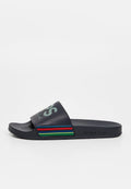 Marineblaue Slide-Sandale mit einem breiten Riemen, der hellgrüne Schrift und bunte horizontale Streifen in Rot, Grün und Blau zeigt. Genoppte Sohle.