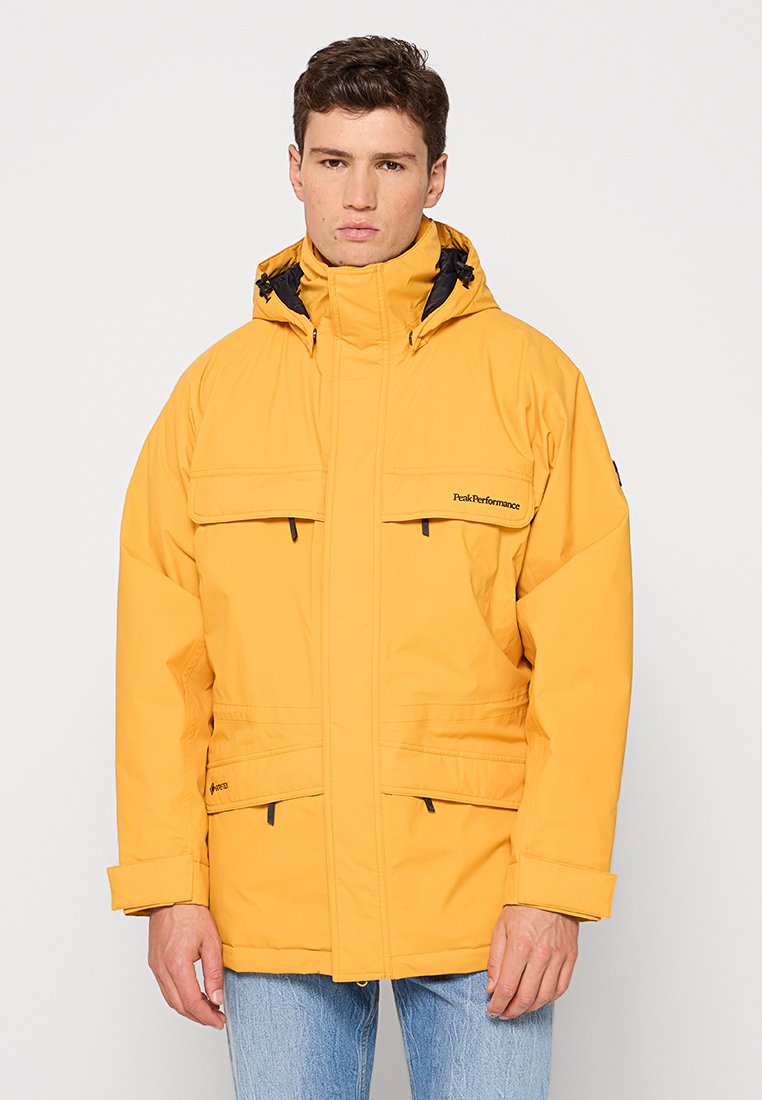 Helle gelbe wasserdichte Jacke mit Kapuze, großen Fronttaschen, schwarzen Akzenten und verstellbaren Bündchen. Leicht und isoliert im Design.