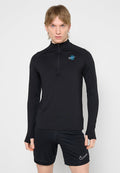 Junge Person mit blondem Haar, die ein schwarzes, langärmliges Sportoberteil mit blauem Logo und schwarze Nike-Shorts vor einem einfarbigen Hintergrund trägt.
