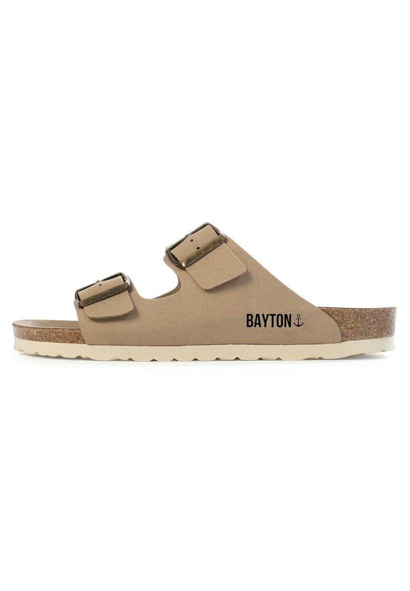 Sandal mit Korksohle in hellbeige, mit zwei verstellbaren Riemen, Metall-Schnallen und einem markierten Logo. Rundliche Zehenpartie und strukturiertes Fußbett.
