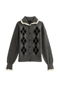Grauer Cardigan mit Karomuster in Schwarz und Weiß, gerippten Bündchen, Rüschensaum und Knopfschluss. Hergestellt aus weichem Strickmaterial.