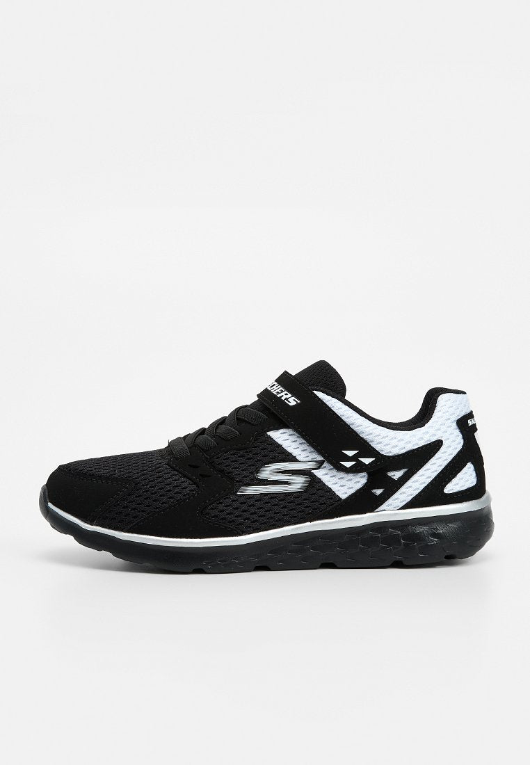 Schwarz-weißer Skechers Sportschuh mit Mesh-Obermaterial, Schnürsenkeln vorne und Klettverschluss auf einfarbigem Hintergrund.