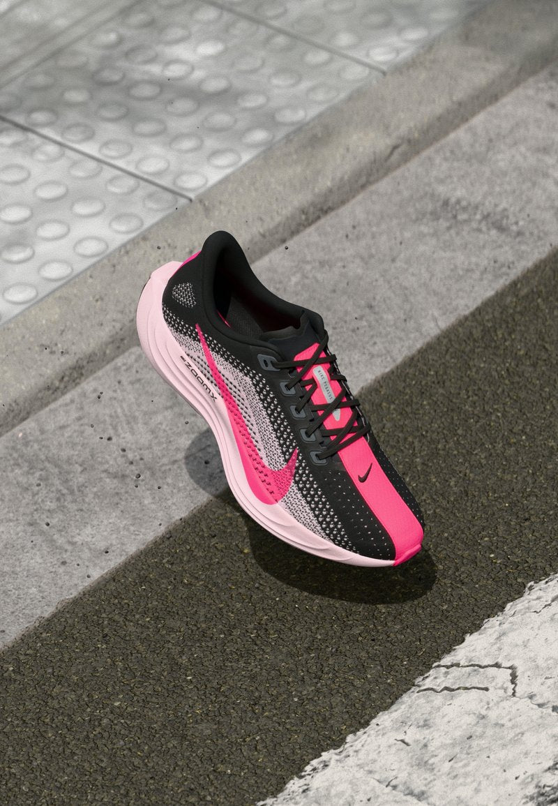Schwarzer und rosa Sportschuh mit einem Obermaterial aus Mesh, kurvenförmiger Gestaltung und Gummisohle. Besitzt ein auffälliges Nike-Swoosh-Logo und ZoomX-Branding.