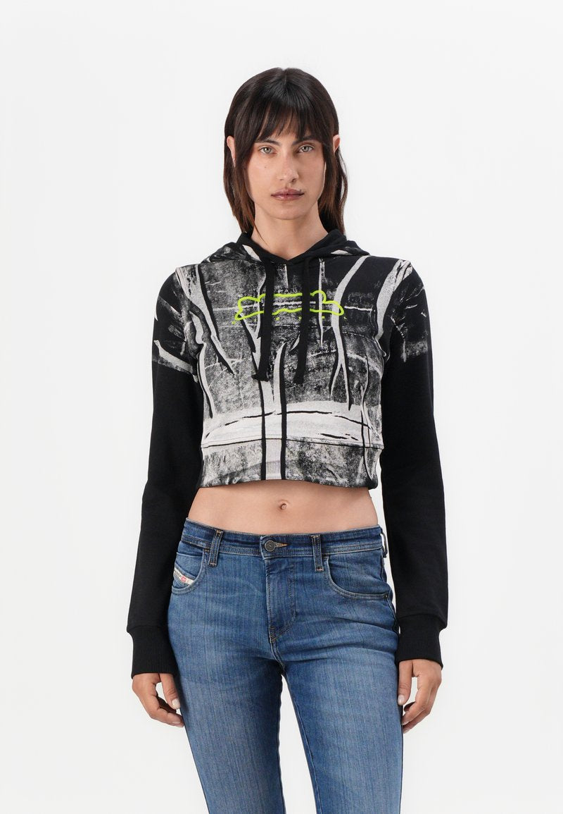 Gekürzter schwarzer Hoodie mit einem grauen abstrakten Muster, Neon-Grünen Akzenten und Kordelzug. Kombiniert mit blauen Jeans. Strukturiertes Material.