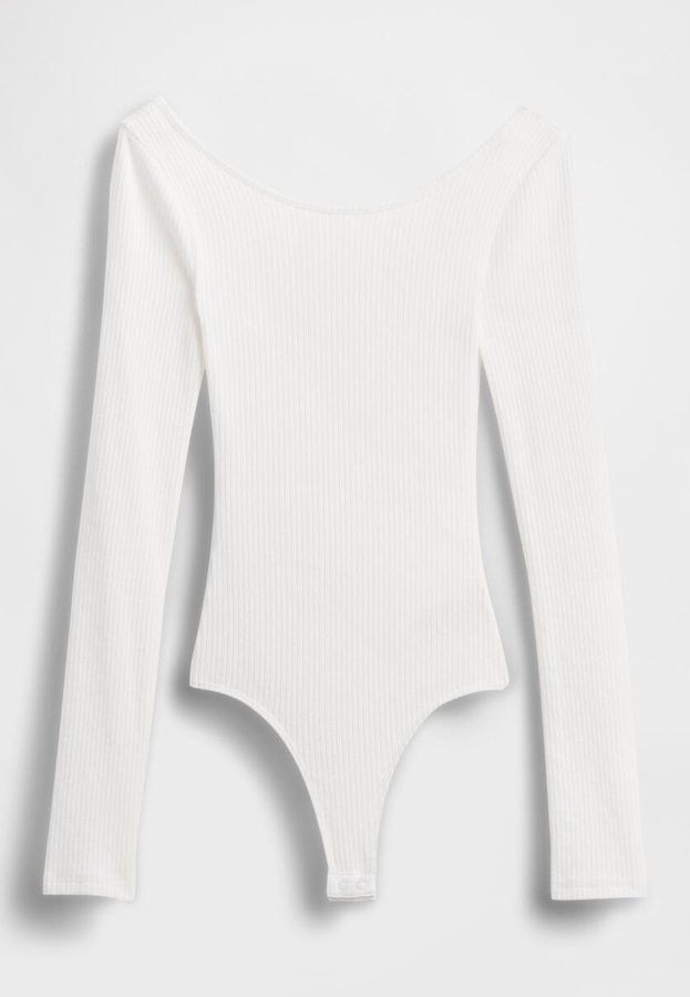 Weißer, gerippter Bodysuit mit langen Ärmeln, schulterfreiem Ausschnitt und String-Unterteil, mit weicher Textur und minimalistischem Design.