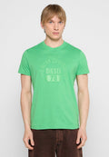 Grünes Baumwoll-T-Shirt mit Rundhalsausschnitt, das ein dezentes geprägtes Logo und eine lässige Passform aufweist, kombiniert mit dunkelbraunen Hosen.