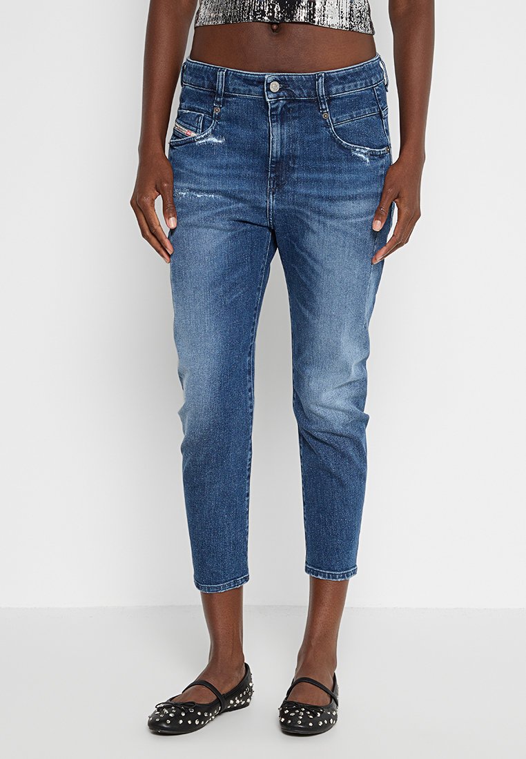 Hellblaue Jeans im Slim-Fit und kürzerer Länge, mit vorderen Taschen und leichter Used-Optik. Getragen mit schwarzen flachen Schuhen.