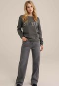 Grauer Sweatshirt mit dem Text "SAMEDI" in mehrfarbigem Stick, kombiniert mit hoch taillierten, weit geschnittenen grauen Jeans. Lässiger, bequemer Schnitt.