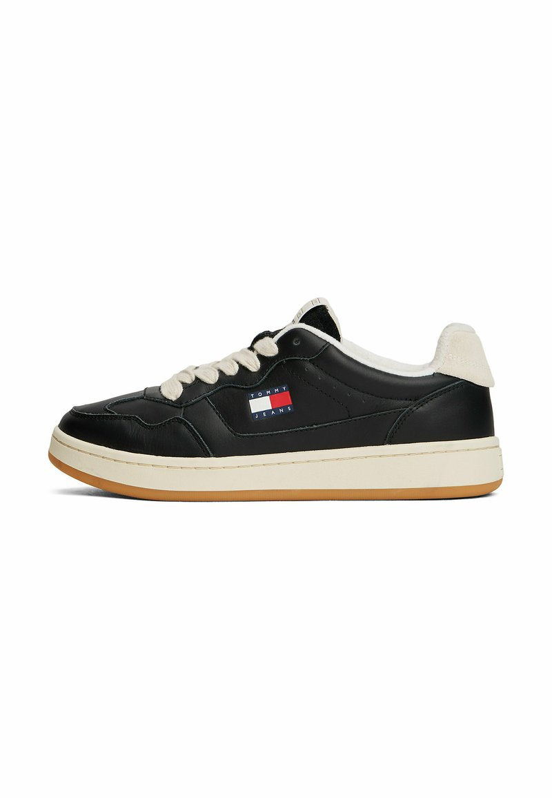 Schwarze Ledersneaker mit cremefarbenen Akzenten, runden Schnürsenkeln, einer dicken weißen Zwischensohle und einem kleinen Markenlogo in Rot und Blau.