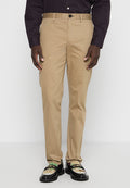 Beige Chinos mit geradem Schnitt und Gürtelschlaufen, mit Knopfverschluss und zwei Fronttaschen, kombiniert mit schwarzen verzierten Slippers.