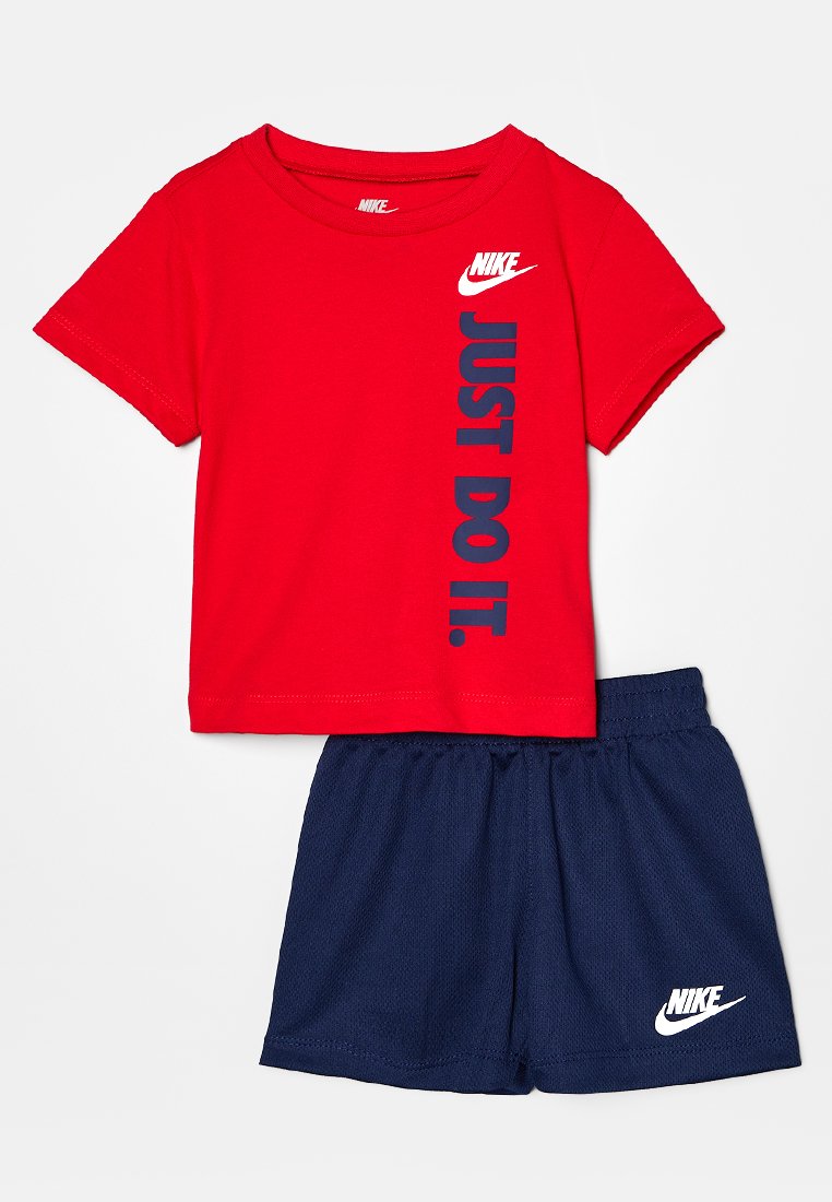 Rotes Baumwoll-T-Shirt mit "JUST DO IT" in Blau, kombiniert mit navyblauen Mesh-Shorts, die am Saum ein weißes Nike-Logo haben.