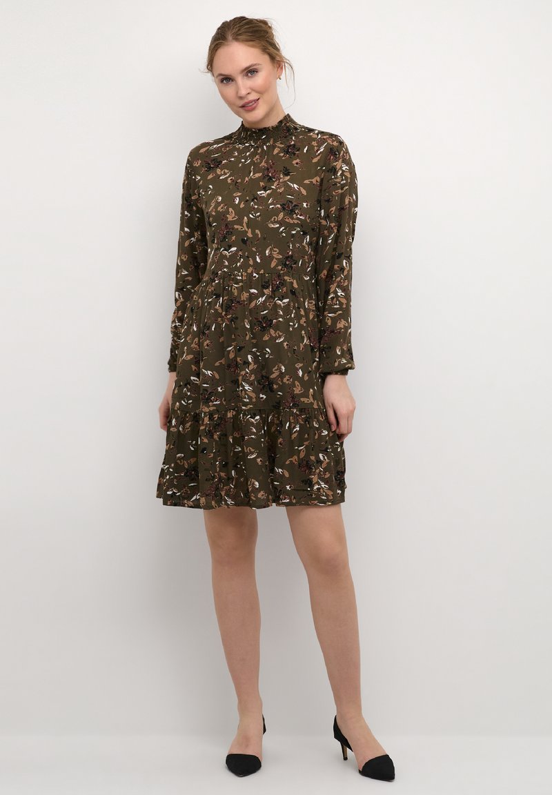 Blumenkleid in Olivgrün mit langen Ärmeln, hohem Kragen, gestuften Design und verschiedenen Farben von Blumen. Der Stoff wirkt leicht und fließend.