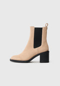 Beige Wildleder-Ankle Boot mit runder Zehenpartie, schwarzen elastischen Seitenpanelen und einem dicken Blockabsatz. Mit einer Schlaufe hinten für ein einfaches Anziehen.