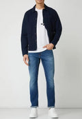 Marineblaues Hemd über einem weißen T-Shirt, kombiniert mit hellblauen Slim-Fit-Jeans und weißen Sneakers. Verfügt über ein lässiges, modernes Design.