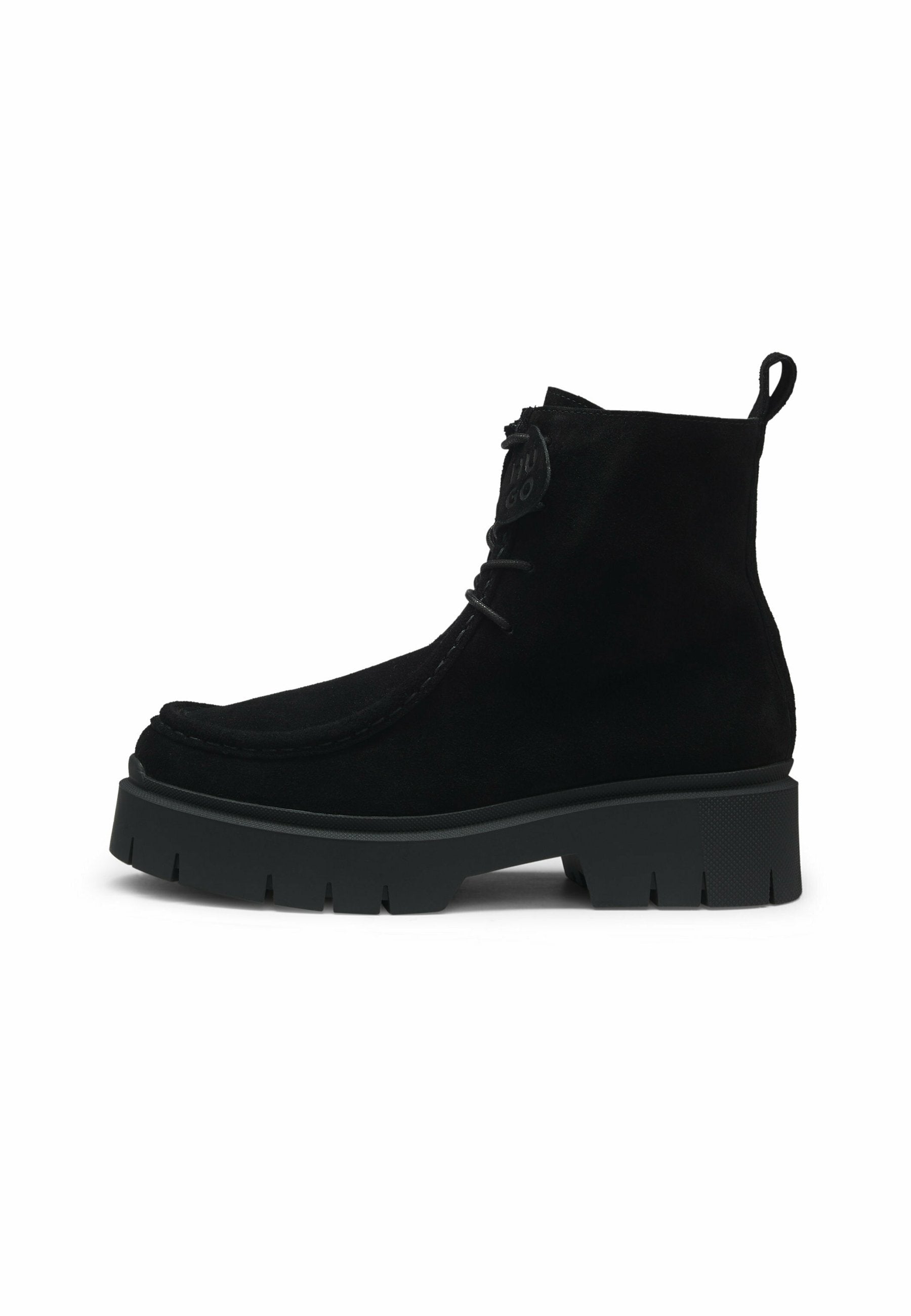 Schwarze Wildleder-Stiefeletten mit einer dicken Gummisohle, einer genähten Verzierung an der Spitze und einer Zuglasche auf der Rückseite für ein müheloses Anziehen.