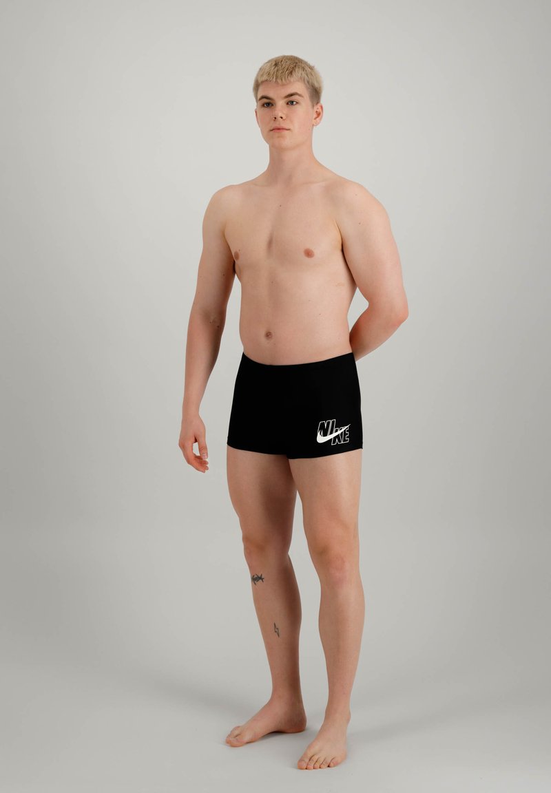 Schwarze Badehosen mit weißem Nike-Logo auf der linken Seite, enganliegendes Design, aus glattem, dehnbarem Material.