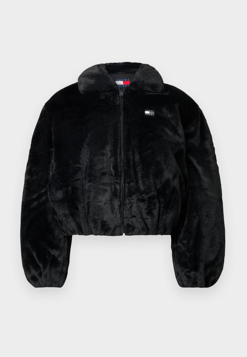 Schwarze kurze Jacke aus weichem Kunstpelz mit Reißverschluss, großem Kragen und elastischem Bund. Verfügt über ein kleines Logo-Patch auf der Brust.