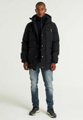 Schwarze gepolsterte Parka mit Kapuze, ausgestattet mit mehreren vorderen Taschen, Reißverschluss- und Druckknopfverschluss, getragen über einem dunklen Rollkragenpullover und hellblauen Jeans.