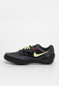 Schwarzer Nike Sportschuh mit gelbem Swoosh, pinken Schnürsenkel-Schlaufen und einem gelben "NIKE"-Riemen über den Schnürsenkeln, seitlich auf einem weißen Hintergrund gezeigt.