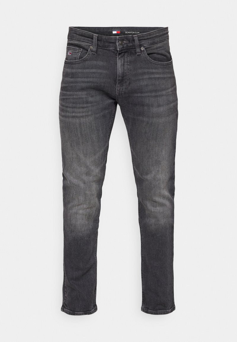Schlanke, dunkelgraue Jeans mit einem verblassten Muster, fünf Taschen und einem Logo am Bund. Einheitliche Farbe mit subtilen Variationen.