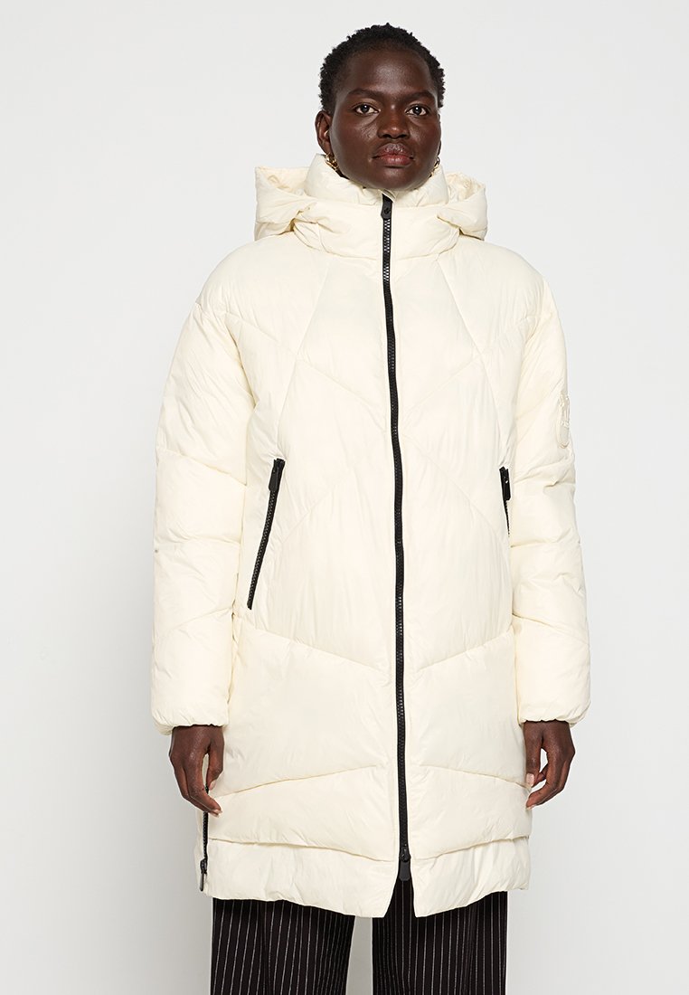 Cremfarbene Daunenjacke mit Kapuze, ausgestattet mit geometrischen Nähten, einem Reißverschluss vorne und seitlichen Taschen mit schwarzen Akzenten. Lange, lockere Passform.