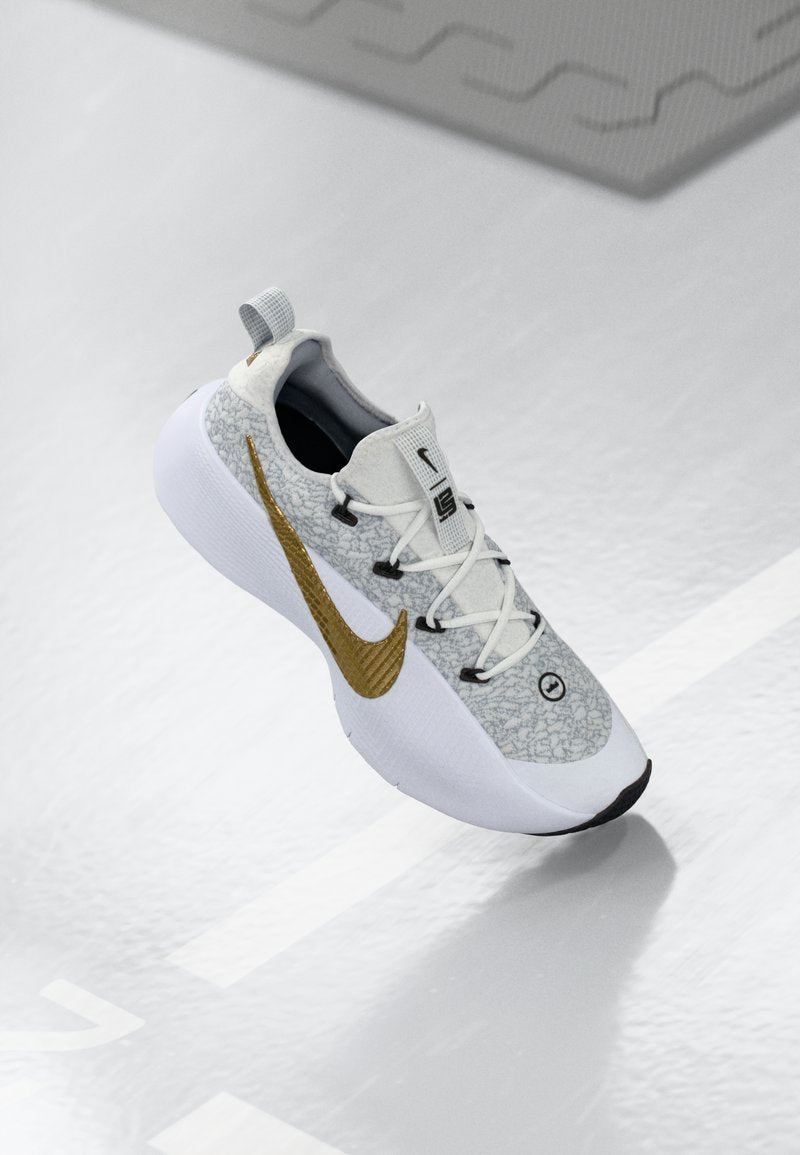 Weiße und graue Sneaker mit einem strukturierten goldenen Nike-Swoosh, weißen Schnürsenkeln und einer dicken weißen Sohle, die über einer reflektierenden Oberfläche schwebt.