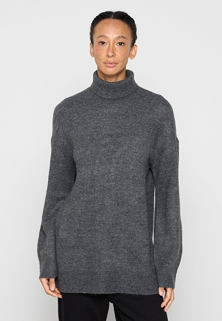 Grauer Rollkragenpullover aus weichem Strickstoff. Er zeichnet sich durch eine lockere Passform mit langen Ärmeln und einen etwas längeren Rückensaum für zusätzlichen Schutz aus.