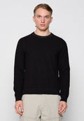 Schwarzer gestrickter Pullover mit geripptem Rundhalsausschnitt, langen Ärmeln und strukturierter Oberfläche. Verfügt über einen geraden Saum und dezente Details am Ausschnitt.