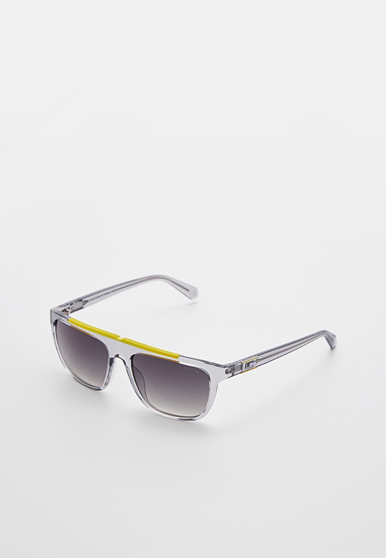 Sonnenbrille mit grauen transparenten Rahmen, gelbem Akzent oben, grauen verlaufenden Gläsern, rechteckiger Form und metallischen Details an den Schläfen.