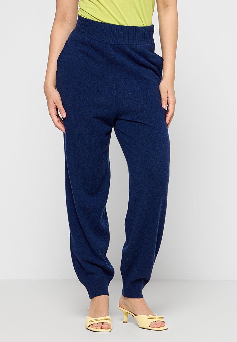 Marineblaue gestrickte Jogginghosen mit einem gerippten Bund und schmal zulaufenden Knöcheln, die einen lockeren Schnitt und eine glatte Textur aufweisen.