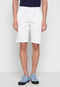 Weiße Baumwollshorts mit geradem Schnitt, umgeschlagenen Säumen und klassischem Knopfverschluss. Kombiniert mit hellblauen Sneakers.