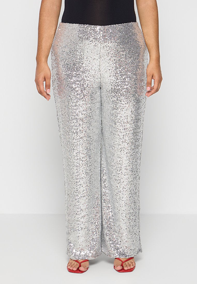 Silberne, glitzernde weite Hosen verfügen über eine reflektierende Textur und einen bequemen Sitz, kombiniert mit einem schwarzen Oberteil und roten Sandalen.