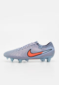 Grauer und orangefarbener Nike-Fußballschuh mit Schnürsenkeln, strukturiertem Obermaterial und geformten Stollen für festen Boden.